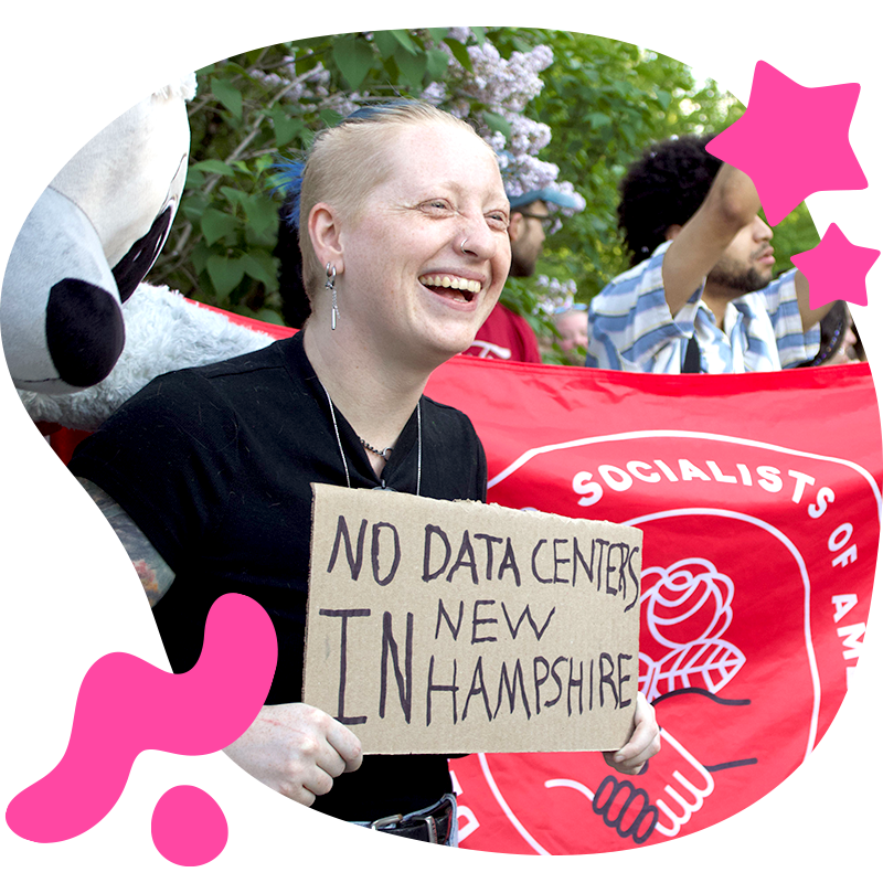 Heather Deiner standing at a protest holding a sign that states "NO DATA CENTERS IN NEW HAMPSHIRE"