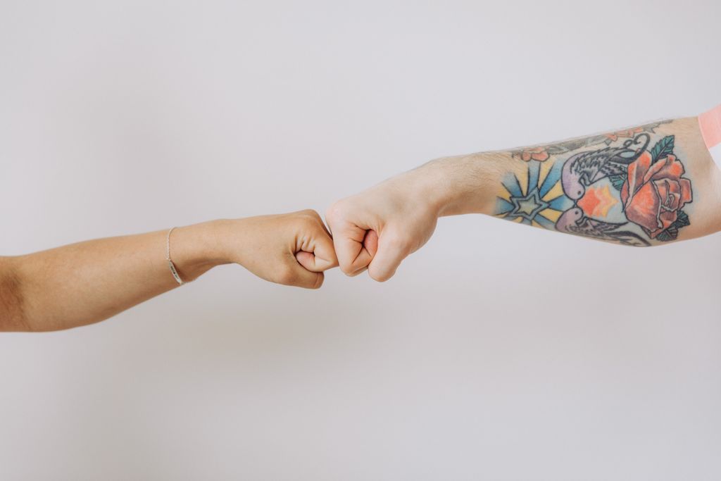 Two fists bumping in agreement, one tattooed, against a white background.